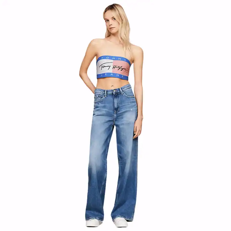 Model poses wearing a Tommy Hilfiger bandeau top and loose fitting jeans