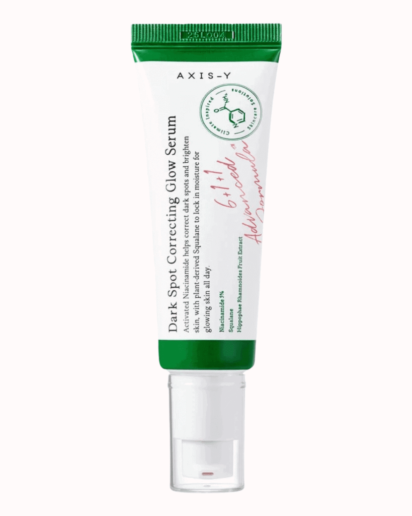 AXIS-Y Dark Spot Correcting Glow Serum tube on a plain pastel pink background