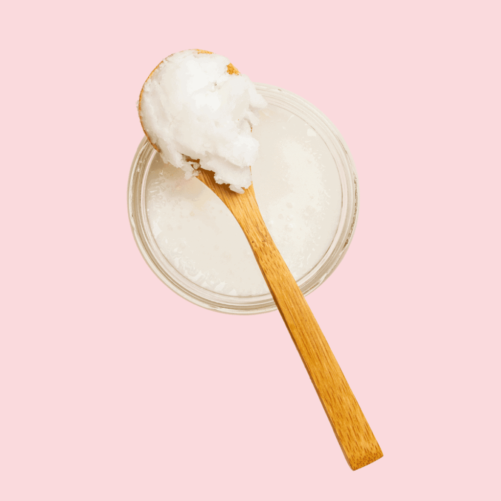 Coconut oil in a jar on a plain pink background. Low porosity hair oils to avoid
