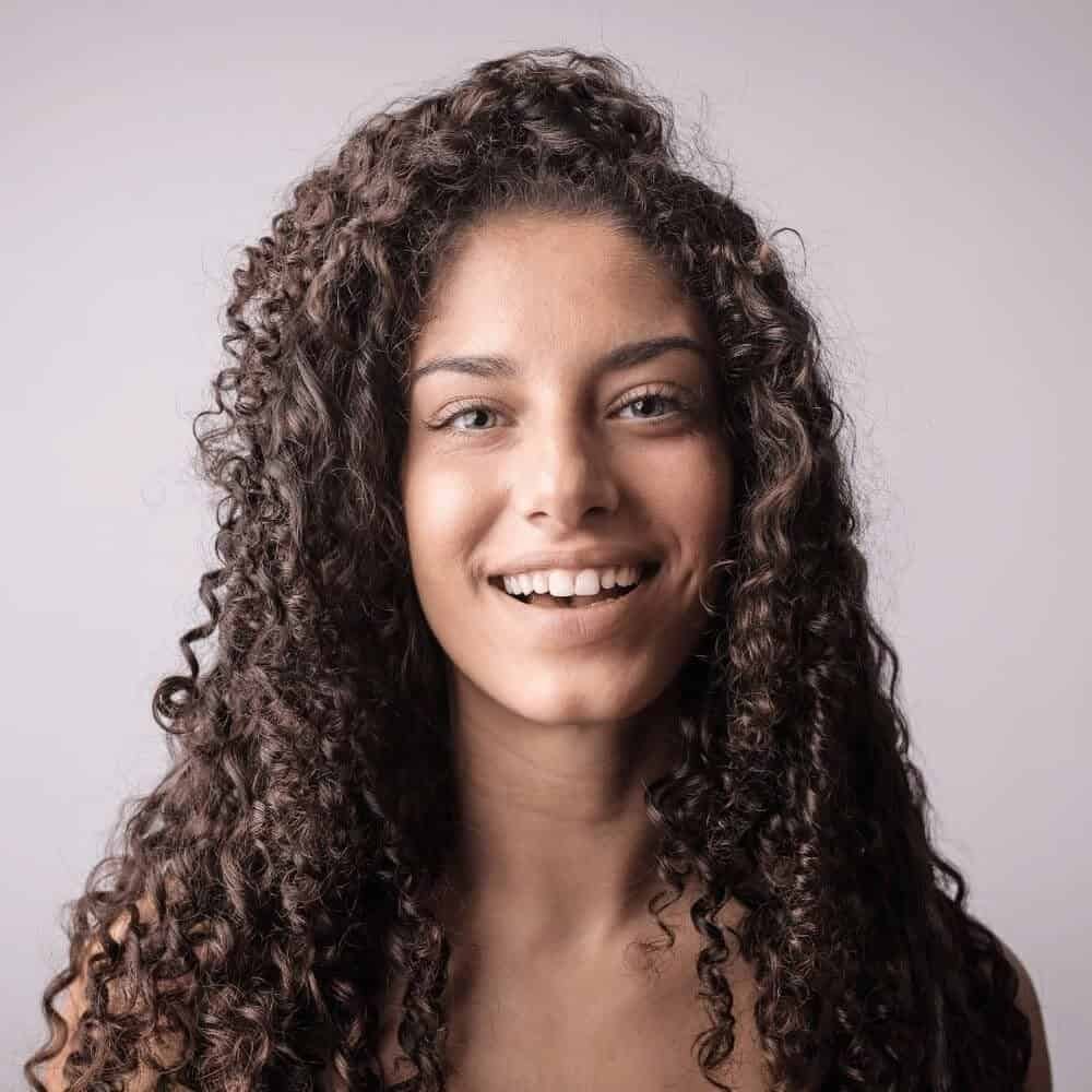 woman with curly hair smiling. Argan oil vs jojoba oil