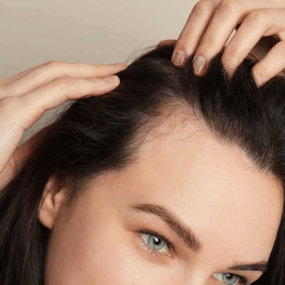 Woman inspecting her hair up close. Clove Oil For Hair Growth