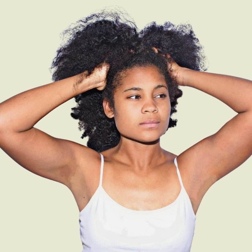 Woman with her hands in her curly hair. Best oils for high porosity hair