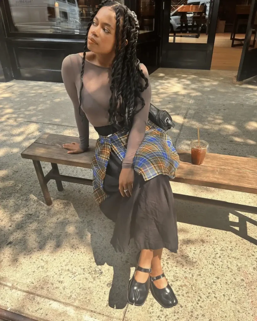 black woman with a brown sheer top and black skirt