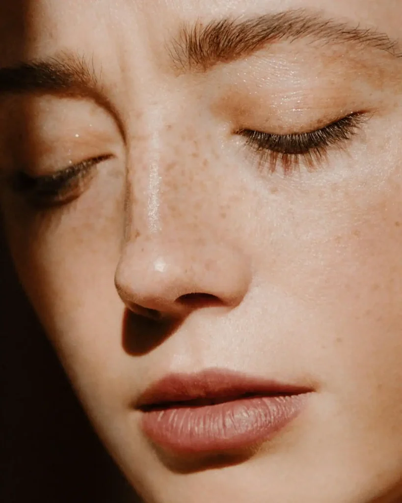 close up of a wowan with freckles. The eyes are almost closed. Argan Oil For Eyelashes