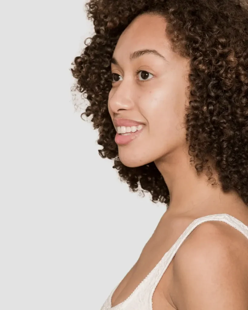 side view of a woman with an afro smiling. Fast Hair Growth Tips for Low Porosity Hair