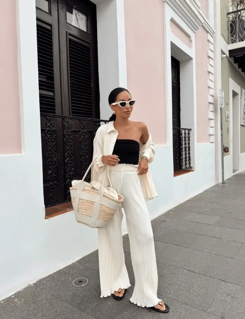 woman weaing a sleeveless black strapless top with white loose trousers. old money outfit