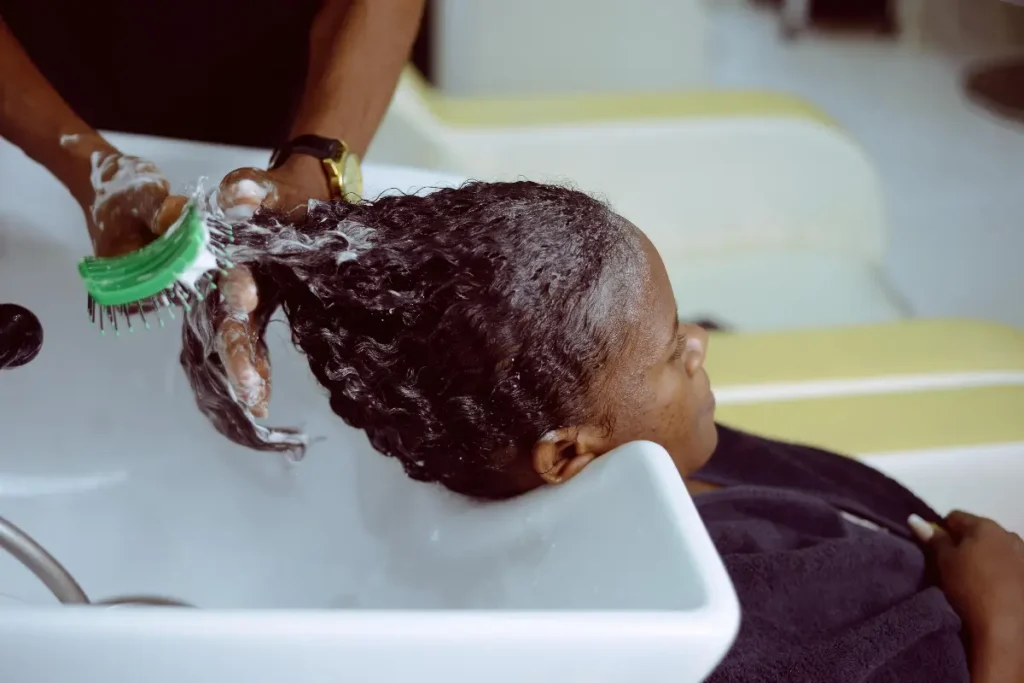 A woman receives a hair wash at a salon with foam and care. Is Coconut Oil Good for Low Porosity Hair