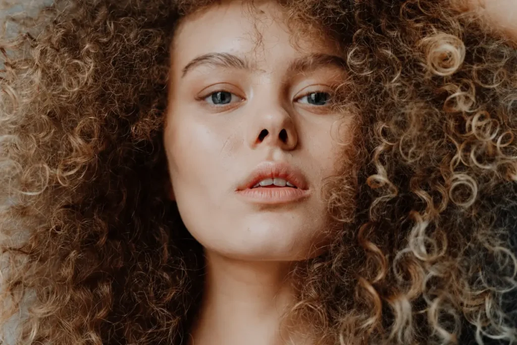 Stunning close-up portrait of a young woman with curly hair, showcasing natural beauty. Is Coconut Oil Good for Low Porosity Hair