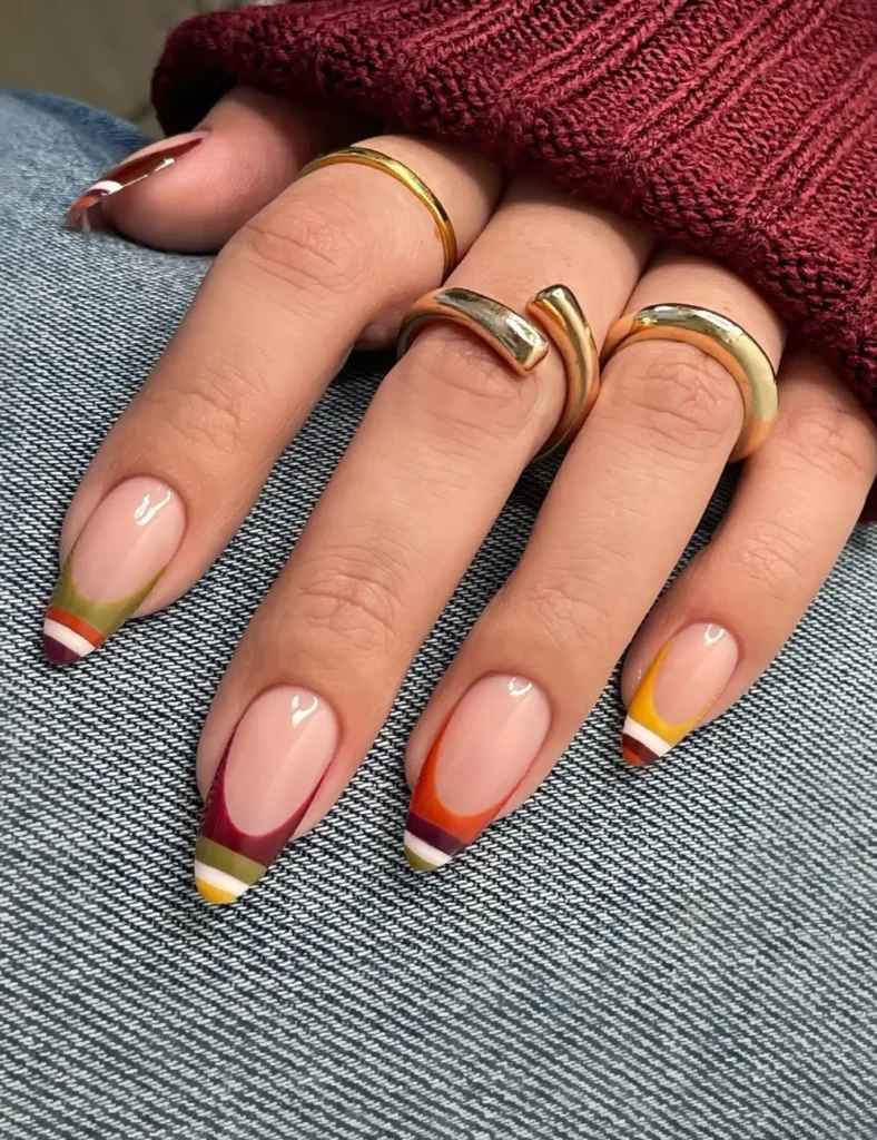 Nude nails with colorful French tips in olive, burgundy, orange, and mustard.
