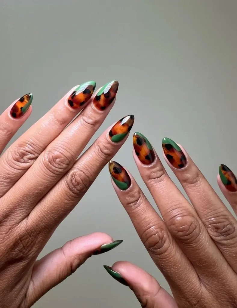 Stiletto nails with tortoiseshell print and emerald green accent design.