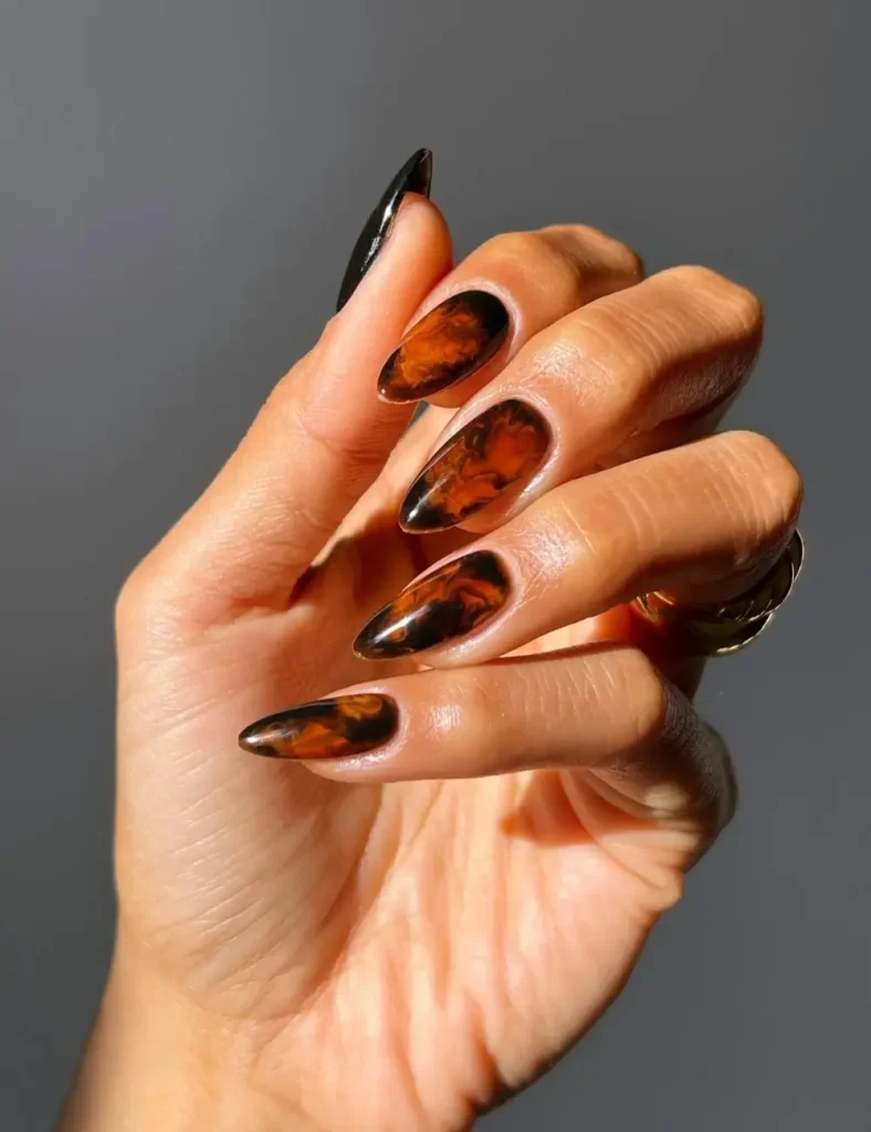 Almond nails with black and burnt orange smoky marble design.