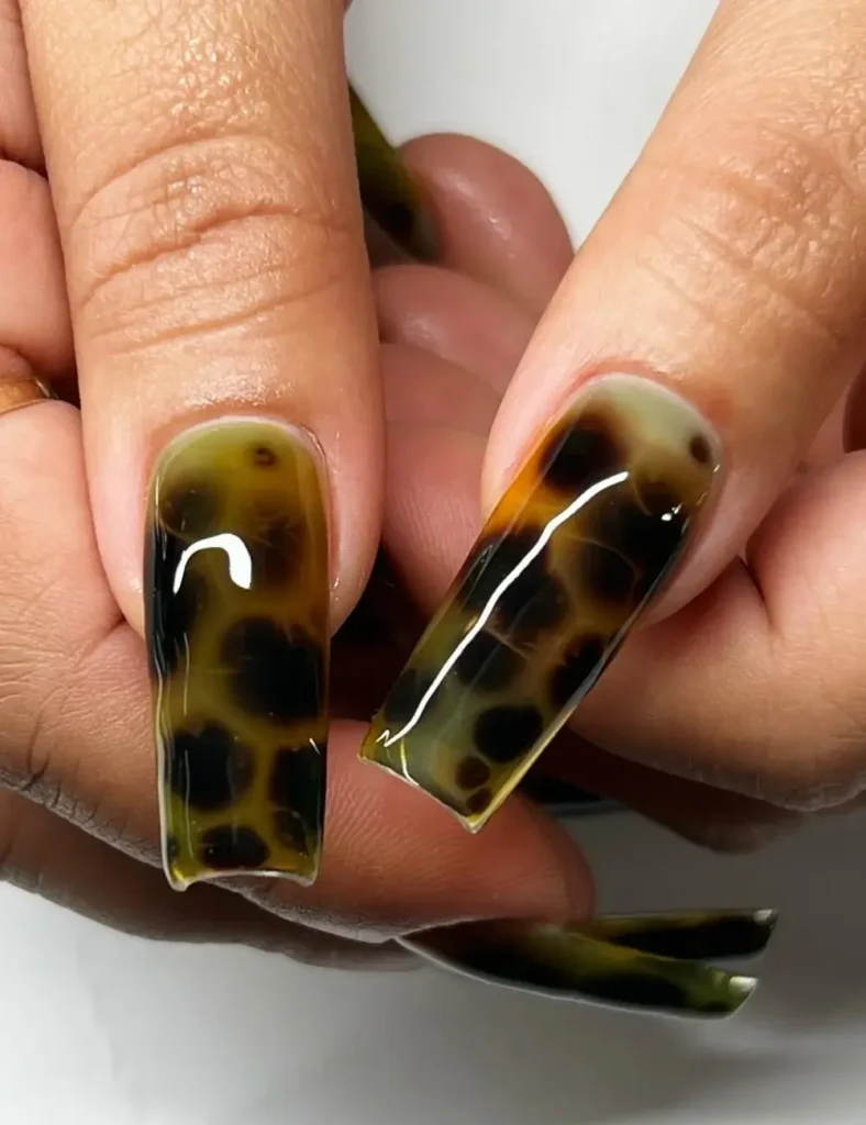 Long square nails with amber and black tortoiseshell nail art design.