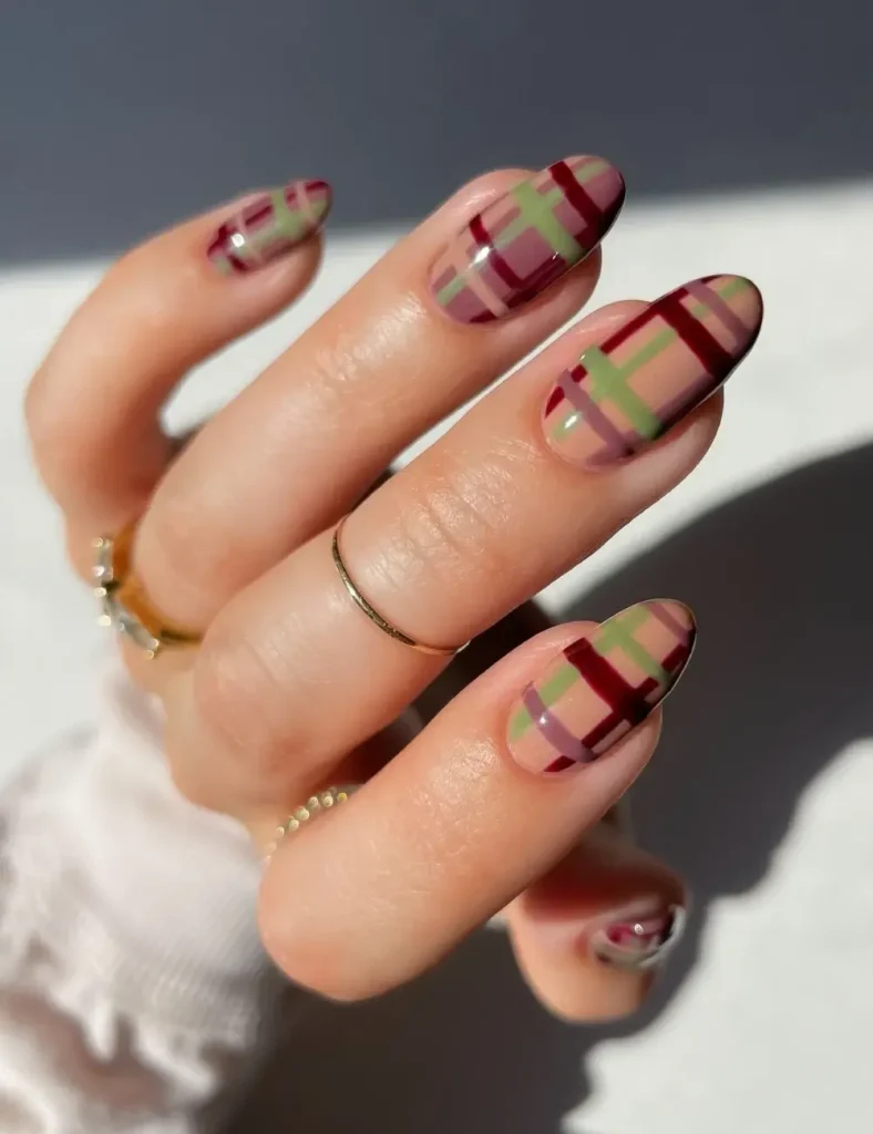 Sheer nude nails with burgundy, olive, and mauve plaid pattern.