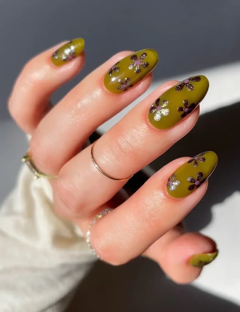 Matte olive green nails with silver and purple glitter daisy accents.