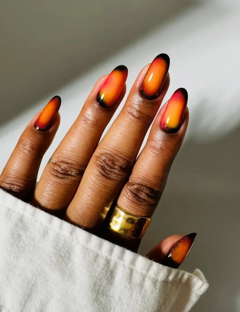 Almond nails with a bright orange and amber center fading into black edges, like glowing embers