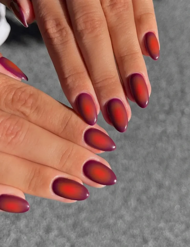 Almond nails with a glowing red-orange center fading into deep berry purple edges