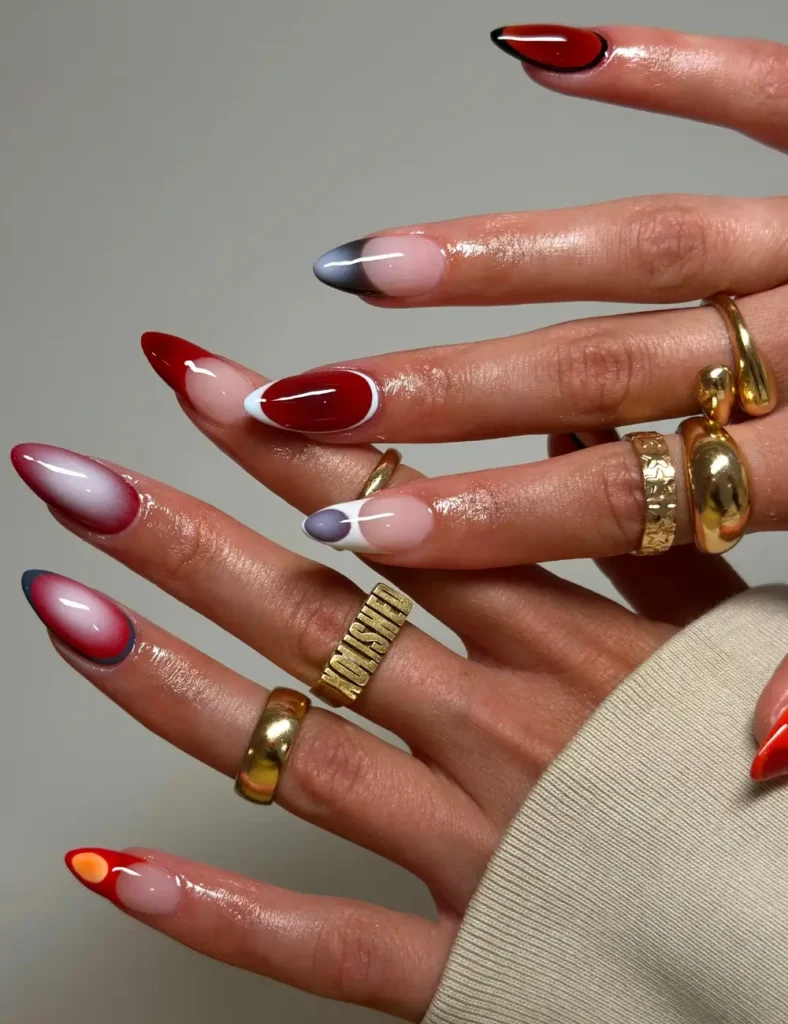 Almond nails with a nude base, red French tips, smoky blue-gray aura tips, white swirl accents, and one solid red nail