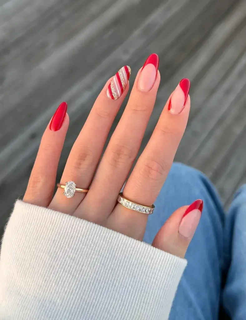 Almond nails with angled red French tips, solid glossy red nails, and one candy cane striped accent nail