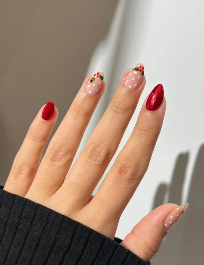 Almond nails with nude bases, tiny holly berry designs and white dots, alongside solid glossy red nails
