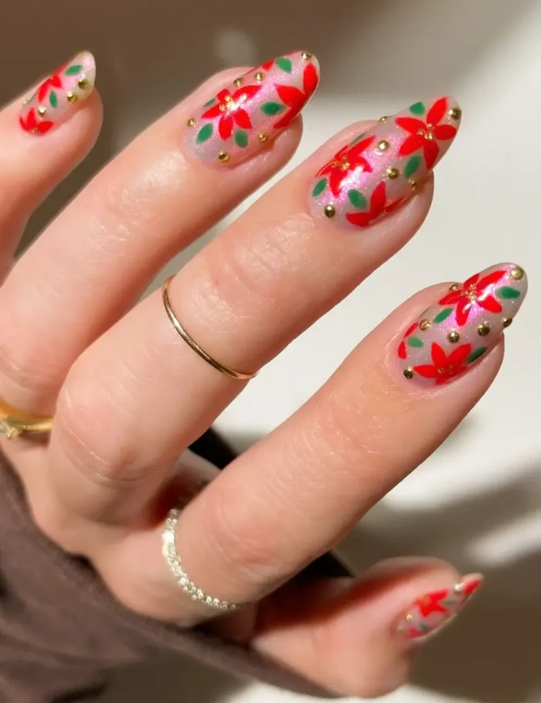 Almond nails with sheer nude bases, hand-painted red poinsettias, green leaves, and gold dot accents