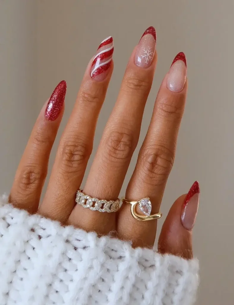 Long almond nails with red glitter, a candy cane striped accent, red French tips, and a nude nail with silver glitter