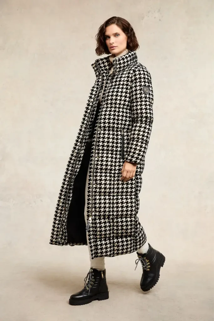 Woman wearing a Holland Cooper Crawford ecru houndstooth longline puffer coat with square quilting and black hardware