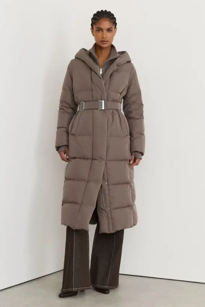 Woman wearing a Reiss Larissa taupe longline quilted puffer coat with a hood and buckled waist belt