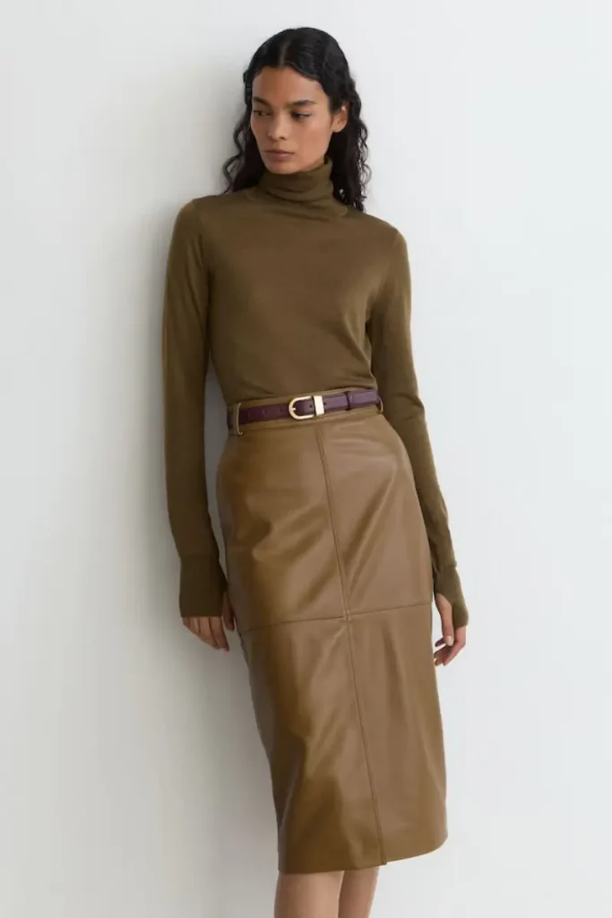 Woman wearing a Reiss Milly khaki green leather midi pencil skirt with seam detailing and a front slit