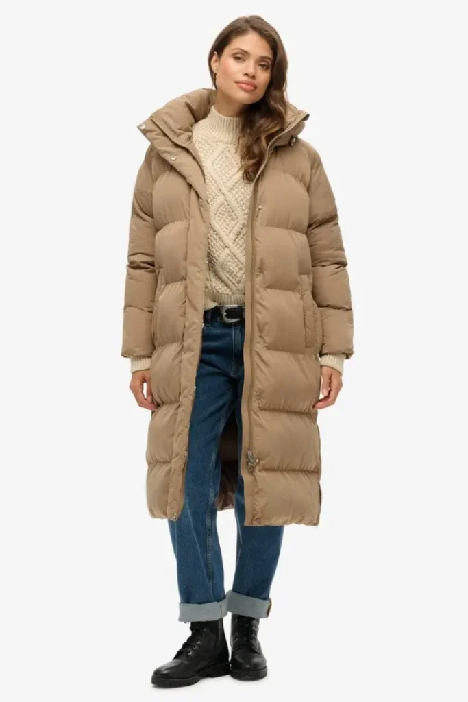 Woman wearing a Superdry oversized fossil brown longline hooded puffer coat with a zip and button front