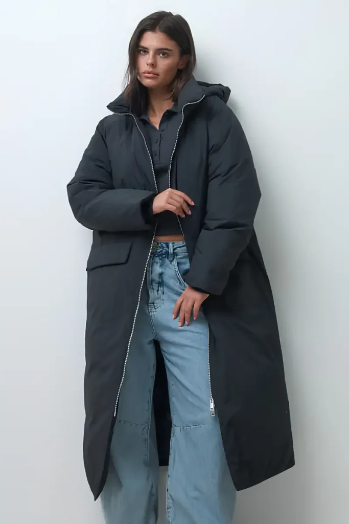 Woman wearing an ASOS DESIGN black longline hooded puffer jacket with a high collar and zip front