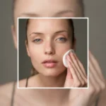 Woman with bare, glowing skin gently pressing a cotton pad to her cheek as part of a skincare routine to reduce the look of open pores on the face.