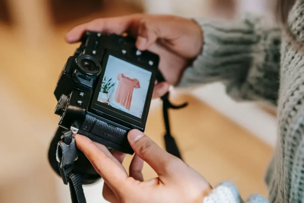 Young female photographer checking digital photos on camera screen indoors with blurred background