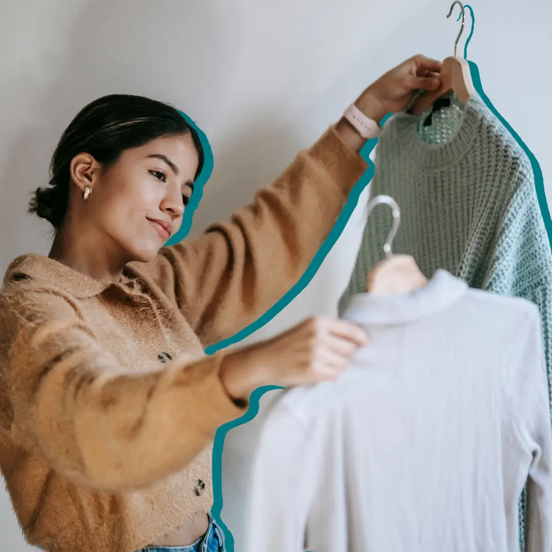 Young woman selecting trendy sweaters indoors, showcasing modern fashion.